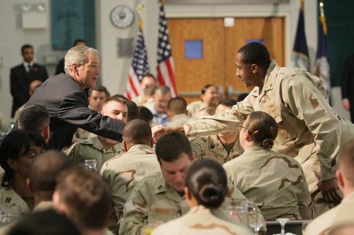 President George W. Bush reaches out to a sailor Sunday, Jan. 13, 2008, during breakfast at the U.S. Naval Forces Central Command in Manama, Bahrain. The President spent the first part of his morning dining with military personnel and coalition forces before departing Bahrain for Abu Dhabi, United Arab Emirates. White House photo by Eric Draper