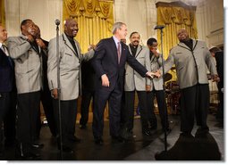 President George W. Bush joins the Temptations on stage in the East Room of the White House Tuesday, Feb. 12, 2008, after they performed during the celebration of African American History Month. White House photo by Eric Draper