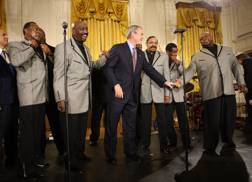 President George W. Bush joins the Temptations on stage in the East Room of the White House Tuesday, Feb. 12, 2008, after they performed during the celebration of African American History Month. White House photo by Eric Draper