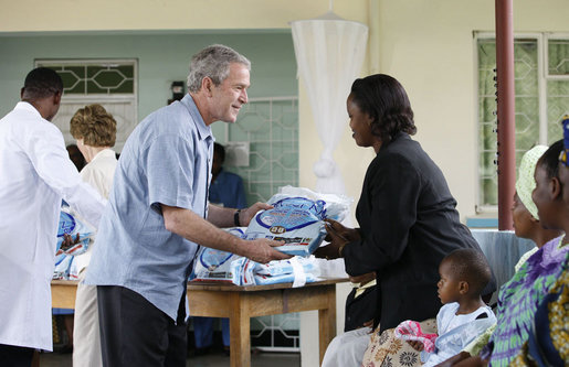 President George W. Bush presents a mosquito net to a patient during a tour Monday, Feb. 18, 2008, of the Meru District Hospital outpatient clinic in Arusha, Tanzania. The mosquito nets are part of a program to help in the battle against malaria. White House photo by Eric Draper