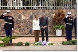 Flanked by saluting U.S. Marines President George W. Bush and Mrs. Laura Bush pause for a moment of silence after laying a wreath on a mass grave at the genocide memorial Tuesday, Feb. 19, 2008, at the Kigali Memorial Centre in Kigali, Rwanda. White House photo by Eric Draper