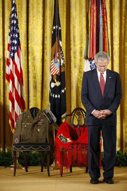 President George W. Bush bows his head during a prayer Monday, March 3, 2008 in the East Room of the White House, standing before two chairs in honor of U.S. Army Master Sgt. Woodrow Wilson Keeble, left, and his wife, Bloosom, moments before presenting members of the Keeble family with the Medal of Honor, posthumously, in honor of Master Sgt. Keeble’s gallantry during his service in the Korean War. Keeble is the first full-blooded Sioux Indian to receive the Medal of Honor. White House photo by Eric Draper