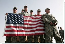 U.S. troops hold the American flag as they await Vice President Dick Cheney's arrival to a rally Tuesday, March 18, 2008 at Balad Air Base, Iraq.  White House photo by David Bohrer