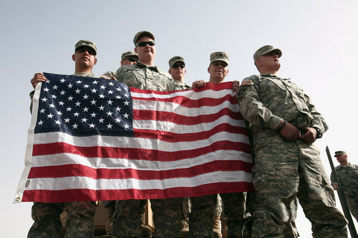 U.S. troops hold the American flag as they await Vice President Dick Cheney's arrival to a rally Tuesday, March 18, 2008 at Balad Air Base, Iraq. White House photo by David Bohrer
