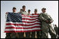U.S. troops hold the American flag as they await Vice President Dick Cheney's arrival to a rally Tuesday, March 18, 2008 at Balad Air Base, Iraq. White House photo by David Bohrer