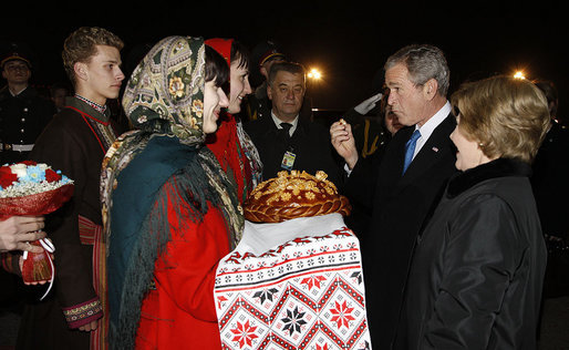 President George W. Bush acknowledges the taste of bread -- presented as a traditional Ukrainian welcome -- as he and Mrs. Laura Bush are greeted upon their arrival Monday, March 31, 2008, at Boryspil State International Airport in Kyiv. White House photo by Eric Draper