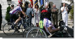 President George W. Bush reaches out to participants of the Wounded Warriors Soldier Ride as they cross in front of him during the kickoff Thursday of the White House to Lighthouse ride. White House photo by Chris Greenberg