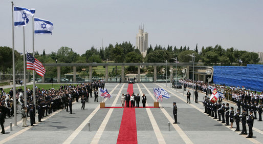 President George W. Bush and Mrs. Laura pause for the raising of the American flag Thursday, May 15, 2008, during arrival ceremonies at the Knesset in Jerusalem. White House photo by Chris Greenberg