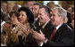 President George W. Bush applauds the entertainment of vocalist Willy Chirino during a Day of Solidarity with the Cuban People Wednesday, May 21, 2008, in the East Room of the White House. Seated next to him are Miguel Sigler Amaya, a former political prisoner, and his wife, Josefa Lopez Pena. White House photo by Joyce N. Boghosian
