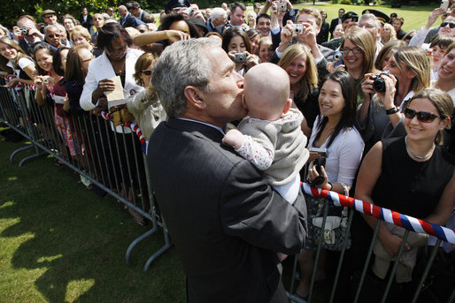 President George W. Bush gives a kiss to a baby during his greeting with members of the U.S. Mission in France, Saturday, June 14, 2008, at the Ambassador's residence in Paris. White House photo by Eric Draper