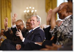 President George W. Bush joins guests in clapping and waving to the music during performances in the East Room of the White House Tuesday, June 17, 2008, in honor of Black Music Month.  White House photo by Eric Draper