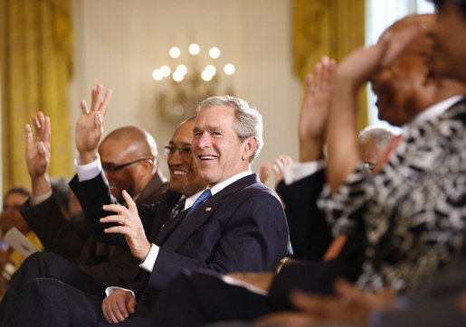 President George W. Bush joins guests in clapping and waving to the music during performances in the East Room of the White House Tuesday, June 17, 2008, in honor of Black Music Month. White House photo by Eric Draper