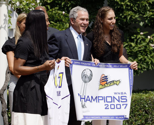 President George W. Bush, joined by Diana Taurasi, left, and Cappie Pondexter, is presented a Phoenix Mercury Championship banner and a personalized team jersey Monday, June 23, 2008, during the 2007 WNBA Champions, the Phoenix Mercury, visit to the White House. White House photo by Eric Draper