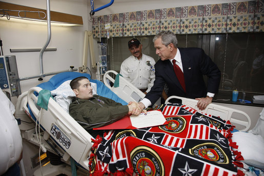 President George W. Bush shakes hands with U.S. Marine Corps Lance Cpl. Justin Rokohl of Orange Grove, Texas, Thursday, July 3, 2008, after awarding Rokohl with a Purple Heart and citation at the National Naval Medical Center in Bethesda, Md. Rokohl's father, John, is seen background. White House photo by Eric Draper