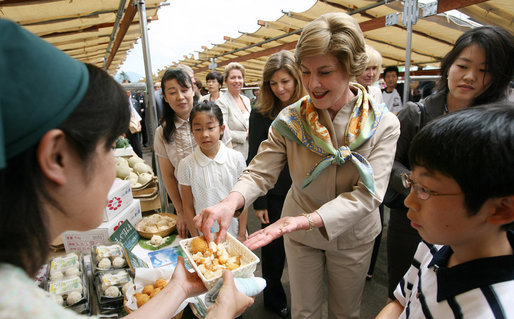 Mrs. Laura Bush tastes a sampling of the food at the Hokkaido Marche farmer's market in Makkari Village Tuesday, July 8, 2008, as part of the G-8 Spouses Program. The small village on the northern Japanese island of Hokkaido is known for its lilies and its potatoes, and the market, organized especially for the occasion of the G-8 Summit, showcased locally grown produce. White House photo by Shealah Craighead