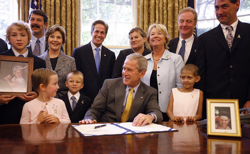 President George W. Bush is joined at his desk by Hannah Lewis, age 7, left, Wyatt Rech, age 6, Eden Adams, age 8, right, Mrs. Laura Bush, other family members, and Sen. Norm Coleman R-MN; Rep. Deborah Pryce R-OH; and Rep. Chris Van Hollen D-MD; Tuesday, July 29, 2008, after signing the Caroline Pryce Walker Conquer Childhood Cancer Act of 2008 in the Oval Office of the White House. White House photo by Eric Draper