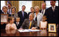 President George W. Bush is joined at his desk by Hannah Lewis, age 7, left, Wyatt Rech, age 6, Eden Adams, age 8, right, Mrs. Laura Bush, other family members, and Sen. Norm Coleman R-MN; Rep. Deborah Pryce R-OH; and Rep. Chris Van Hollen D-MD; Tuesday, July 29, 2008, after signing the Caroline Pryce Walker Conquer Childhood Cancer Act of 2008 in the Oval Office of the White House. White House photo by Eric Draper