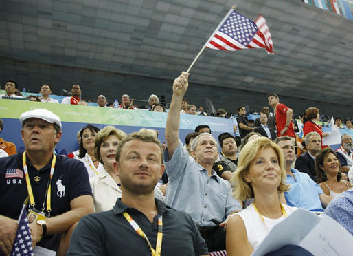 President George W. Bush, accompanied by Mrs. Laura Bush, waves an American flag as he cheers for the U.S. Olympic swimming team Monday, Aug. 11, 2008, in the National Aquatic Center at the 2008 Summer Olympic Games in Beijing. White House photo by Eric Draper