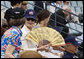 Mrs. Laura Bush wearing a U.S. Olympic baseball team hat uses a fan to keep cool as she watches the U.S. Olympic men's baseball team play a practice game against the Chinese Olympic men's baseball team Monday, Aug. 11, 2008, at the 2008 Summer Olympic Games in Beijing. White House photo by Eric Draper