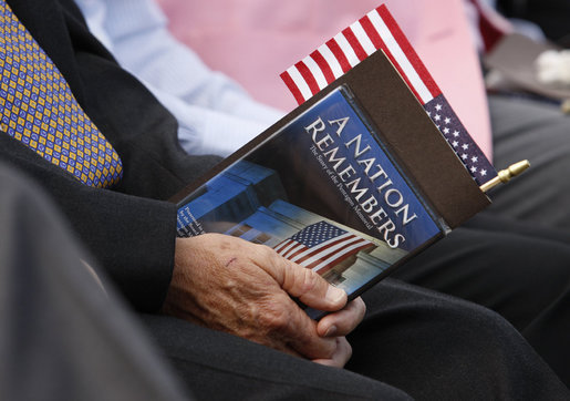 An audience member holds a flag and a commemorative program during the dedication ceremony of the 9/11 Pentagon Memorial Thursday, Sept. 11, 2008, at the Pentagon in Arlington, Va. White House photo by Eric Draper