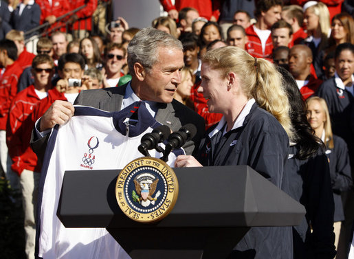 President George W. Bush is presented a team jacket from Paralympian Jennifer Armbruster after delivering his remarks to members of the 2008 United States Summer Olympic and Paralympic Teams Tuesday, Oct. 7, 2008, on the South Lawn of the White House. White House photo by Eric Draper