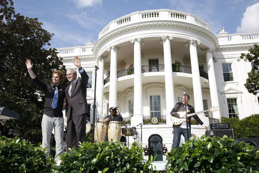 President George W. Bush is joined by Colombian musician Andres Cabas as they wave to invited guests, following Cabas and his band's performance Thursday, Oct. 9, 2008 on the South Lawn of the White House, during the celebration of Hispanic Heritage Month. White House photo by Eric Draper
