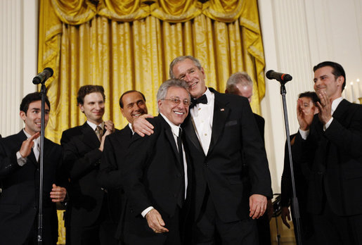 President George W. Bush, joined on stage by Italian Prime Minister Silvio Berlusconi, embraces singer Frankie Valli, lead singer of The Four Seasons, invited on stage Monday evening, Oct. 13, 2008, following a performance of the Broadway cast of the Jersey Boys in the East Room of the White House. White House photo by Eric Draper
