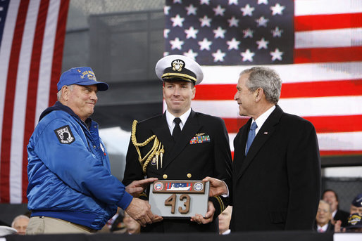President George W. Bush is presented a piece of the flight deck of the USS Intrepid by Mike Hallahan, left, president of the United War Veterans Council of New York, also joined by military aide U.S. Navy Lt.Cmdr. Clay Beers, during the rededication ceremony Tuesday, Nov. 11, 2008, for the Intrepid Sea, Air and Space Museum in New York. White House photo by Eric Draper