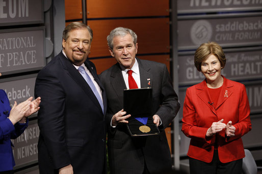 President George W. Bush, joined by Mrs. Laura Bush, is presented with the International Medal of PEACE by Pastor Rick Warren, Monday, Dec. 1, 2008, following their participation at the Saddleback Civil Forum on Global Health in Washington, D.C. White House photo by Eric Draper