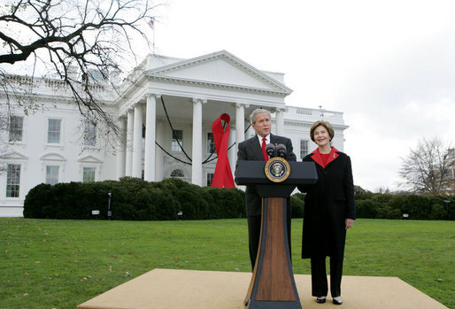 President George W. Bush and Mrs. Laura Bush address reporters on World AIDS Day from the North Lawn of the White House, Monday, Dec. 1. 2008, where President Bush reaffirmed the commitment to fight HIV/AIDS at home and abroad. A large red ribbon is displayed from the North Portico of the White House in observance of World AIDS Day. White House photo by Joyce N. Boghosian