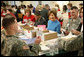 Mrs. Laura Bush is seated between volunteers Master Tre'shaad Cox, 11, left, and U.S. Army Sgt. Thomas Griffin, an out-patient at Walter Reed Army Medical Center, during a visit Saturday, Dec. 6, 2008, to the American Red Cross Holiday Mail for Heroes Packing Event at the Red Cross National Headquarters in Washington, D.C. Mrs. Bush reminded the volunteers that during this holiday season, "we are reminded of our many blessings, especially our freedom. The American Red Cross Holiday Mail for Heroes project, in partnership with Pitney Bowes, provides citizens an opportunity to send holiday cards to members of our Armed Forces. I am grateful to the many volunteers gathered here today to ensure our military receives our message of thanks for the sacrifice they make each day to defend our freedom." White House photo by Chris Greenberg