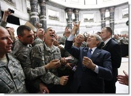 President George W. Bush gestures the "hook'em horns" sign of the University of Texas to U.S. military personnel in the balcony, as he meets with U.S. military and diplomatic personnel Sunday, Dec, 14, 2008, at the Al Faw Palace-Camp Victory in Baghdad.  White House photo by Eric Draper