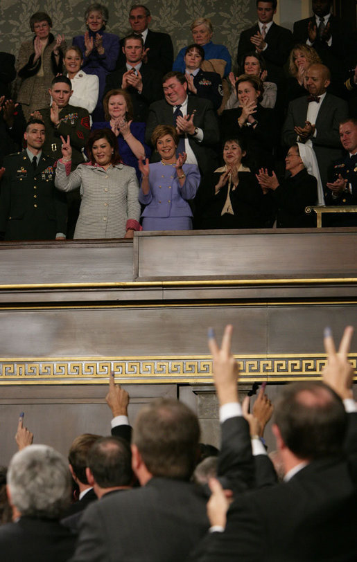 Safia Taleb al-Suhail, a guest of President and Mrs. Bush, holds up stained fingers marking her vote in Iraq elections as members of Congress, in a show of support, hold up fingers stained during the State of the Union, Feb. 2, 2005. White House photo by Eric Draper