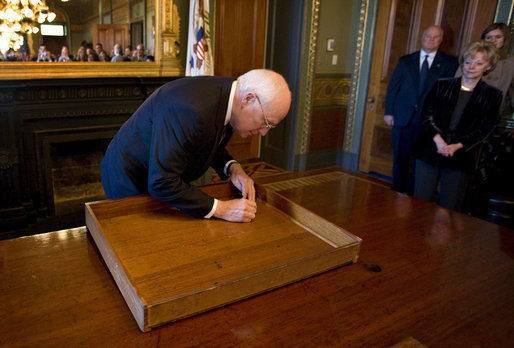 Vice President Dick Cheney signs the inside of the top drawer of his desk in the Vice President's Ceremonial Office Monday, Jan. 12, 2009, at the Eisenhower Executive Office Building in Washington, D.C. The desk, constructed in 1902 and first used by President Theodore Roosevelt, has been signed by various presidents and vice presidents since the 1940s. Mrs. Lynne Cheney is seen at right. White House photo by David Bohrer
