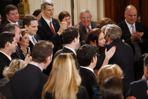 President George W. Bush embraces his daughters Barbara and Jenna as he receives a standing ovation from invited guests and members of his staff and Cabinet at the conclusion of his televised farewell address to the nation Thursday evening, Jan. 15. 2009, in the East Room of the White House. White House photo by Chris Greenberg
