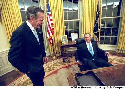  President George W. Bush sits at his desk in the Oval Office for the first time on Inaugural Day. He talks with his father, former President George H.W. Bush.