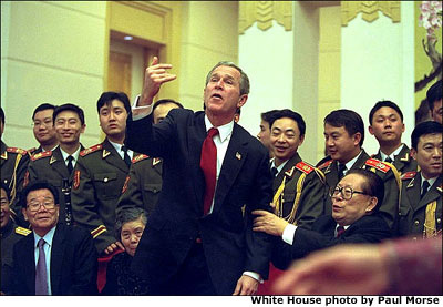 President George W. Bush motions for someone to join him and Chinese President Jiang Zemin for a group photo during a dinner in Beijing, China, Thursday, Feb. 21, 2002. White House photo by Paul Morse.