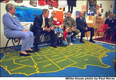 Photograph of the President with children. A map of the United States is on the carpet. White House photo by Paul Morse.