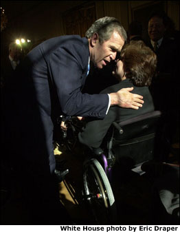 President Bush hugs a woman in a wheelchair during the New Freedom Initiative announcement. White House photo by Eric Draper.