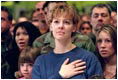 Family members of Air Force personnel place their hands over their hearts at Elmendorf Air Force Base in Anchorage, Alaska, Feb. 16, 2002. "I'm honored to be in a place where people understand the need for sacrifice and patriotism," said the President. "And I've come to Alaska to let you know that I'm proud of our United States military; that when I sent you into action, I knew you would not let this nation down."