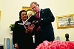 President George W. Bush and Coretta Scott King meet in the Oval Office February 25, 2004 and review a book dedicated to her husband entitled 