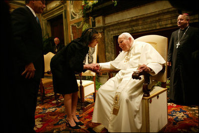 Mrs. Bush takes the hand of Pope John Paul II during the June 2004 visit to Rome by her and President Bush during which they presented the Pope with the Medal of Freedom.
