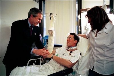 President George W. Bush shakes hands with Army SFC Thomas Douglas of Fayetteville, N.C., after presenting him with the Purple Heart at Walter Reed Army Medical Center in Washington, D.C., Friday, April 11, 2003. Also pictured is Mr. Douglas' wife, Donna Douglas.