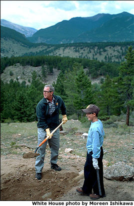 Working for his share of the picnic bounty, President Bush helps build a trail at Rocky Mountain National Park in Estes, Colo., Aug. 14. After sharing lunch with YMCA volunteers, the President addressed the media. "And I want to thank all the Park Service employees who are here. You've got a tough job and an important job," said the President. White House photo by Moreen Ishikawa.
