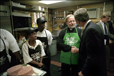 Visiting the kitchen of So Others Might Eat charity, President George W. Bush greets director Father Adams and other volunteers at the Washington D.C. site Nov. 20. Started in 1970, the program serves breakfast and lunch daily to the homeless. President Bush is encouraging Americans to give to charities.