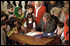 Surrounded by children, President George W. Bush signs the "Afghan Women and Children Relief Act of 2001" at the National Women's Museum in the Arts, Dec. 12, 2001. "The overwhelming support for this legislation sends a clear message: As we drive out the Taliban and the terrorists, we are determined to lift up the people of Afghanistan," said the President in his remarks.