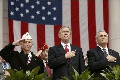 President George W. Bush stands with National Commander of the Army and Navy Union David Berger, left, and Secretary of Veterans Affairs Anthony Principi during the Veterans Day ceremonies at Arlington National Cemetery Tuesday, Nov. 11, 2003. "We observe Veterans Day on an anniversary -- not of a great battle or of the beginning of a war, but of a day when war ended and our nation was again at peace," said the President. "Ever since the Armistice of November the 11th, 1918, this has been a day to remember our debt to all who have worn the uniform of the United States."