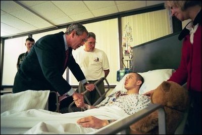 President George W. Bush speaks to U.S. Army Corporal James Rednour, of Ft. Campbell, Kentucky, after presenting him The Purple Heart for injuries Cpl. Rednour sustained while serving in Iraq. President Bush visited troops at Walter Reed Army Medical Center in Washinton, D.C., Thursday, December 18, 2003. Cpl. Rednour’s parents, Chuck and Cindy look on.