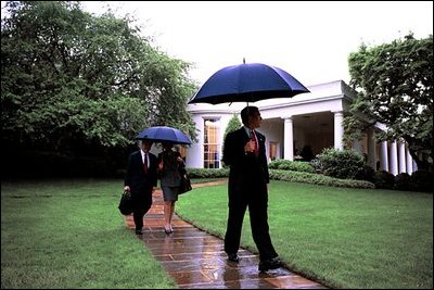 President George W. Bush departs the White House under a spring shower May 9, 2003. He is followed by Chief of Staff Andrew Card, left, and National Security Advisor Dr. Condoleezza Rice. 