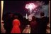 As explosions of color light up the night sky and the glowing faces of guests, the two first couples watch fireworks from the Truman Balcony. 